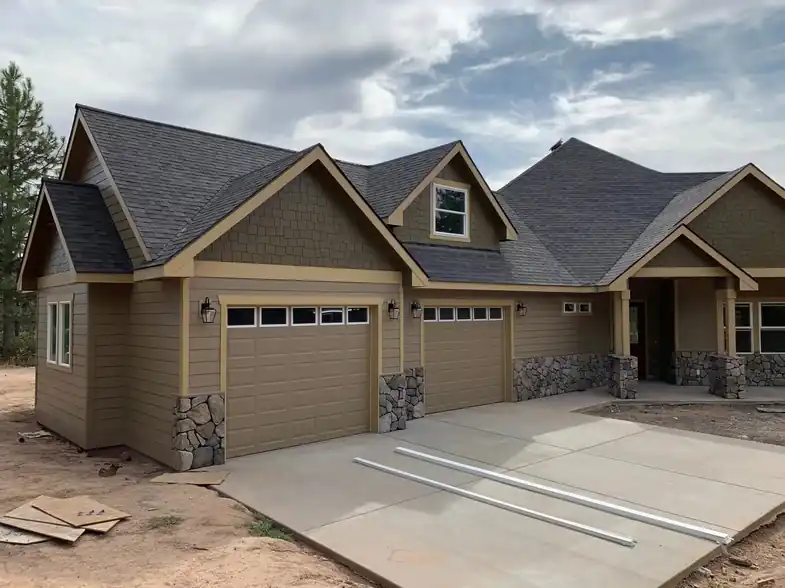 The finished craftsman home with stone wainscot and a three-car garage, pine trees behind