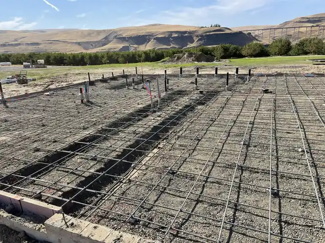A rebar grid and stem walls laid out for a slab with hills in the background