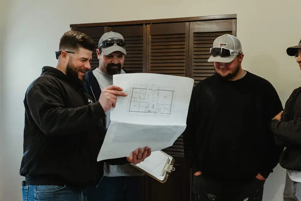 Three men laughing together while reviewing a floor plan