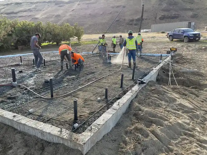 A crew in hi-vis shirts placing and finishing a concrete slab