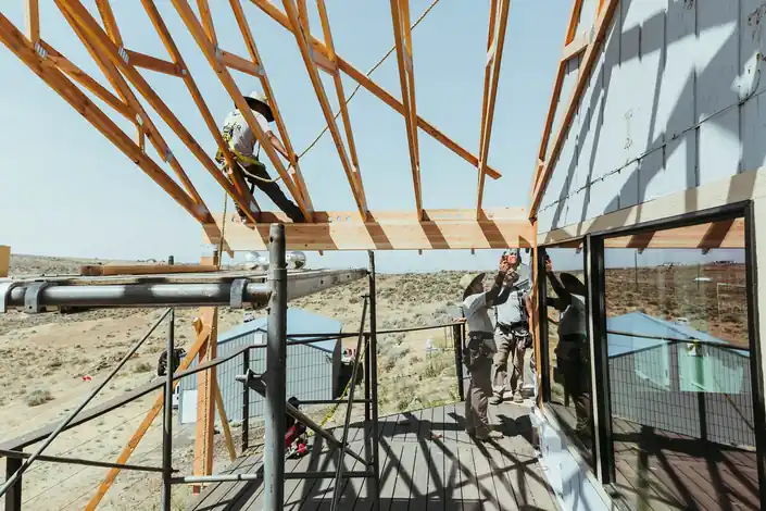 A carpenter on scaffolding fixing trusses on a covered deck