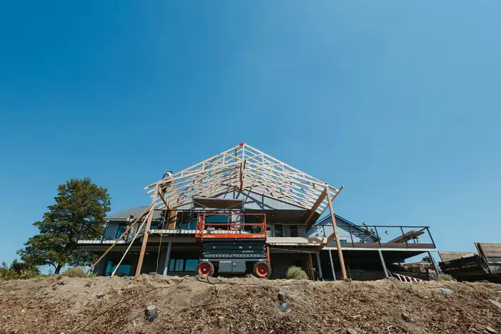 Roof trusses going up on a house on a ridge under a deep blue sky