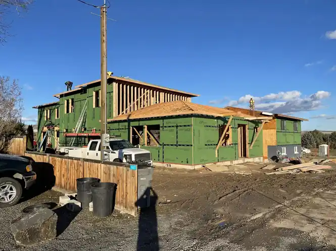 A two-storey addition wrapped in green ZIP sheathing